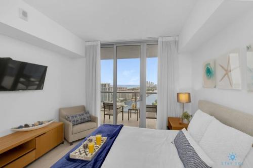 a bedroom with a bed and a television and a balcony at Infinite View - Balcony- Amazing Pool- Near Beach in Hallandale Beach