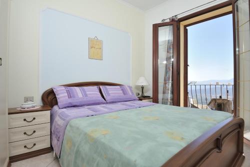 een slaapkamer met een bed met paarse lakens en een balkon bij Apartments Baunei in Baunei