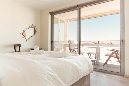 a bedroom with a large white bed and a balcony at Living Stone - Beryl in Athens