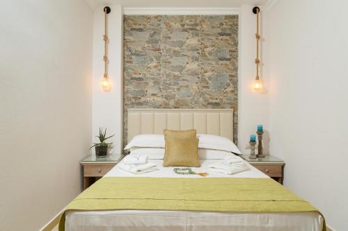 a bedroom with a bed with a stone wall at Mandani Villa luxury apartments in Limenas