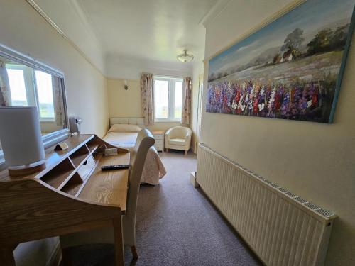 a bedroom with a desk and a painting on the wall at Schoolhouse Restaurant and Hotel in Swindon