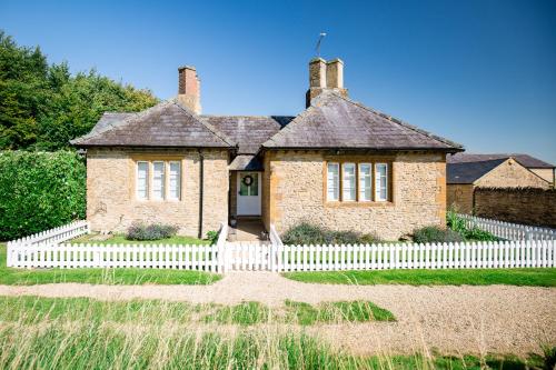 an old brick house with a white fence at The Cotswold Hideaway - Boutique Cottage in Long Compton