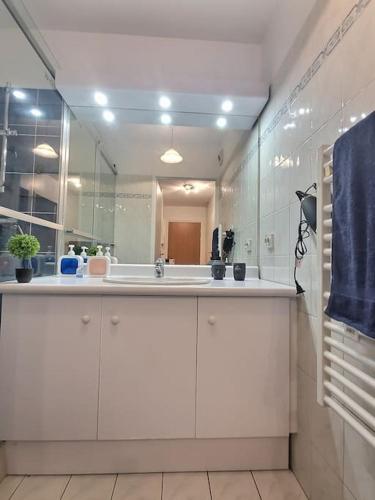 Baño blanco con lavabo y espejo en Appartement a proximité aéroport paris Orly en Antony