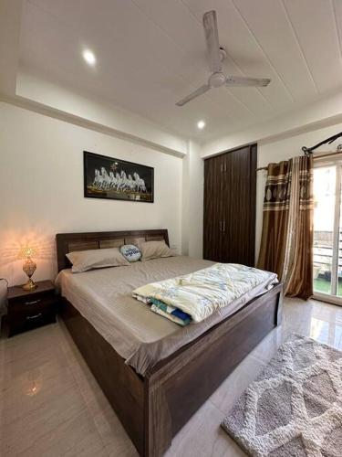 een slaapkamer met een groot bed en een plafondventilator bij Your cozy home in Dehradun