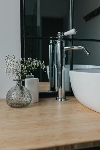 un comptoir de salle de bain avec un lavabo et un miroir dans l'établissement Les Fleurs de Maria, à Le Bourg-Dun