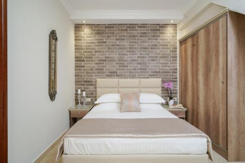 a bedroom with a large bed and a brick wall at Mandani Villa Luxury Apartments in Limenas