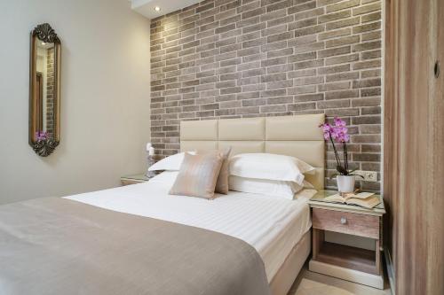 a bedroom with a large bed with a brick wall at Mandani Villa Luxury Apartments in Limenas