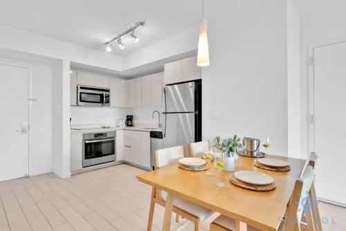 a white kitchen with a wooden table and chairs at Modern Condo - Amazing Pool - Gym - Balcony in Hallandale Beach