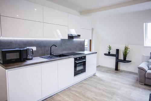 a white kitchen with a sink and a microwave at Rezidence Petra Voka in Třeboň