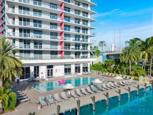 a resort pool with lounge chairs and a large building at Modern Condo - Amazing Pool - Gym - Balcony in Hallandale Beach