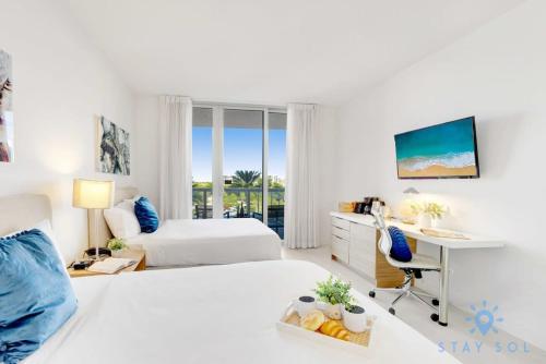 a bedroom with two beds and a desk with a computer at Balcony - Pool - Near Beach - Gym in Hallandale Beach