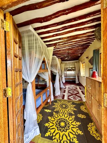 a room with three bunk beds and a ceiling at Kameleon Blue in Kizimkazi