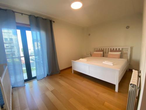um quarto com uma cama branca e uma grande janela em Bom dia Parque Nações LisboaZ em Lisboa