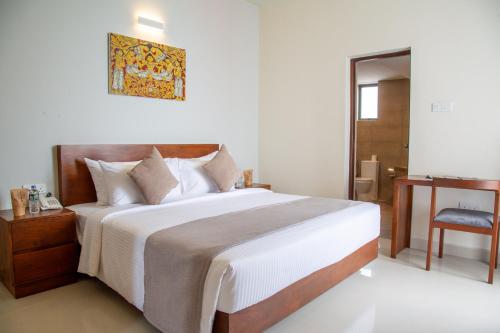 a bedroom with a large bed and a chair at Marine Suites in Colombo