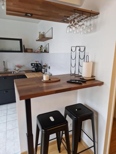 a kitchen with a wooden counter with two stools at Chez Valérian, gare de Chantilly in Chantilly