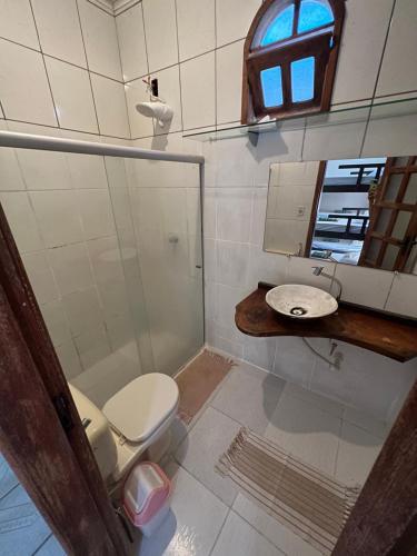 a bathroom with a toilet and a sink and a mirror at Aluê Hostel in Arraial d'Ajuda