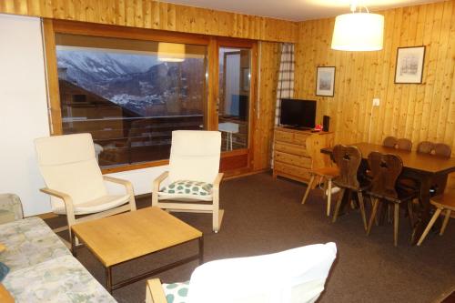 ein Wohnzimmer mit einem Tisch, Stühlen und einem TV in der Unterkunft Beaulieu COSY & CENTER apartments in Veysonnaz