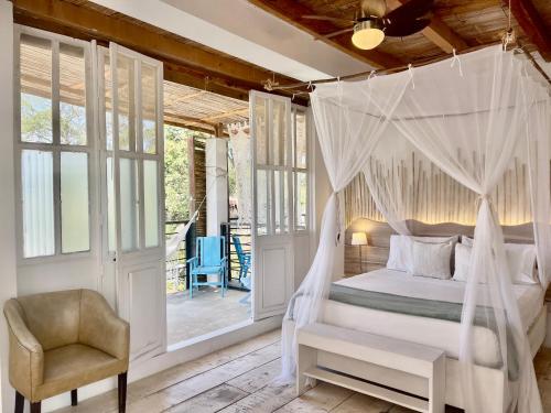 a bedroom with a canopy bed and a chair at Casa Kai in Palomino