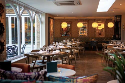 un comedor con mesas, sillas y ventanas en Harbour Hotel & Spa Richmond, en Richmond upon Thames