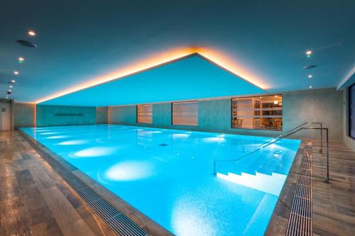 - une grande piscine avec éclairage bleu dans un bâtiment dans l'établissement Harbour Hotel & Spa Richmond, à Richmond upon Thames