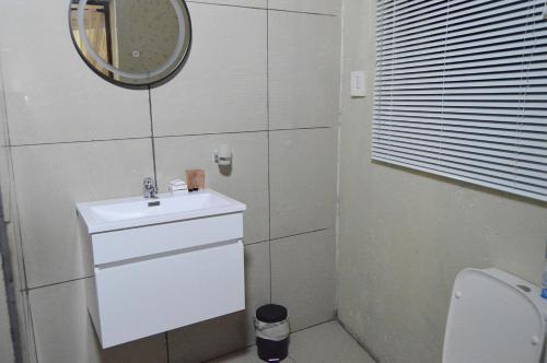 ein weißes Badezimmer mit einem Waschbecken und einem Spiegel in der Unterkunft Pan African Lodge & Safari in Marloth Park