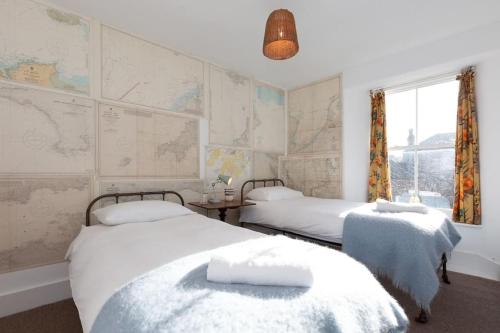 two beds in a room with maps on the wall at Janies Cottage~ Mousehole~Eclectic Interiors & Vintage Charm in Mousehole