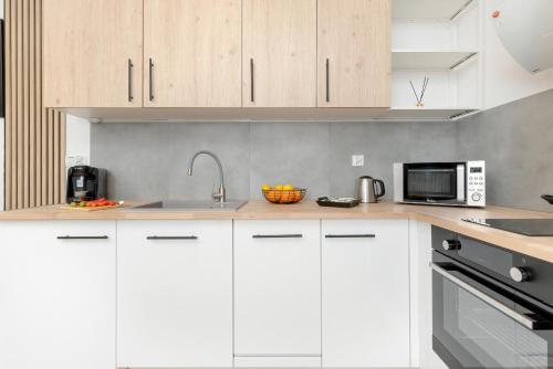 a kitchen with white cabinets and a microwave at Stylish Bright Apartment Starowiejska near Arena Gdańsk with Balcony & Parking by Renters in Gdańsk