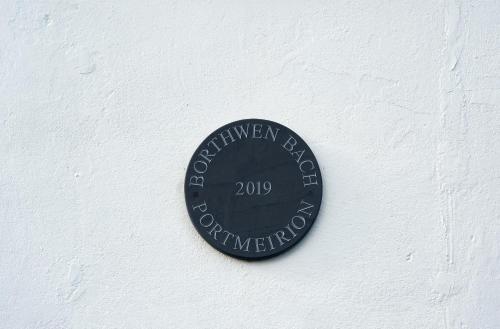 a black plaque on a white wall at Portmeirion Village & Castell Deudraeth in Porthmadog