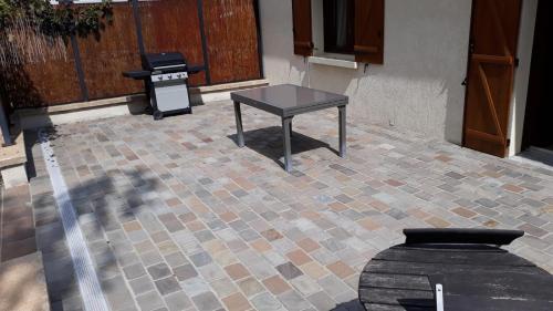 - une table assise sur une terrasse en briques avec un grill dans l'établissement maison 1 chambre, à Samois-sur-Seine