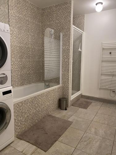 a bathroom with a tub and a washing machine at Chambre confort centre ville chez l'habitant in Lyon
