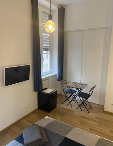 a living room with a table and chairs and a tv at Chambre confort centre ville chez l'habitant in Lyon