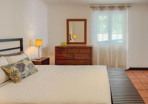 1 dormitorio con cama, tocador y espejo en WelcomeBuddy - Casa Tia Néné - Green Glassyard, en Lagoa