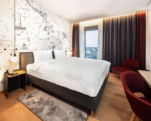 a bedroom with a large bed and a red chair at IntercityHotel Paderborn in Paderborn