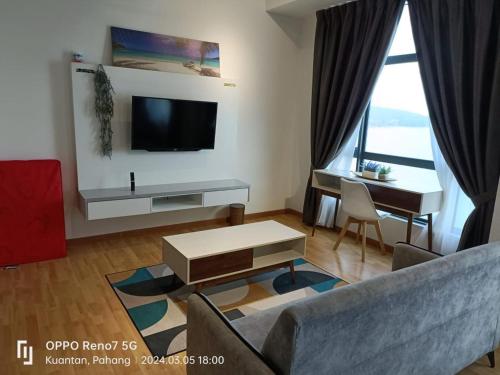 a living room with a couch and a tv and a table at Kuantan Imperium seaview cityview by Avenzee in Kuantan