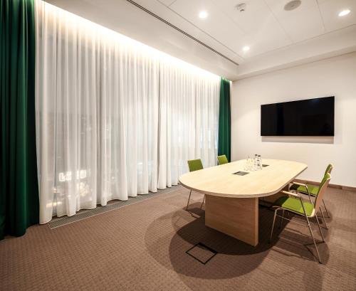 a conference room with a table and a flat screen tv at IntercityHotel Paderborn in Paderborn