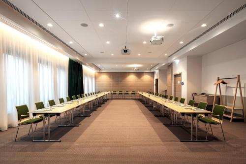 a conference room with long tables and green chairs at IntercityHotel Paderborn in Paderborn