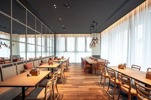 a restaurant with wooden tables and chairs and windows at IntercityHotel Paderborn in Paderborn