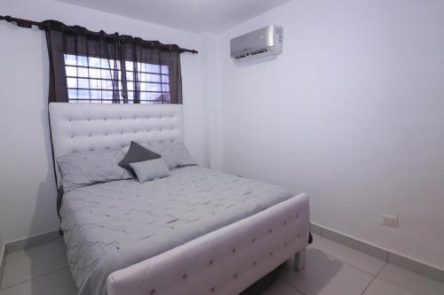 a small bed in a room with a window at 3 BR apartment - READY for your stay WIFI Pool Great Location in Santiago de los Caballeros