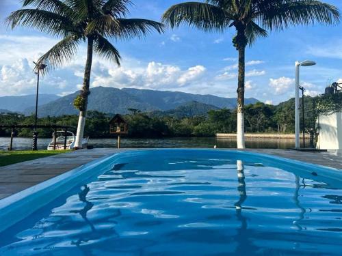 einen Pool mit Palmen und Bergen im Hintergrund in der Unterkunft Angra dos Sonhos in Angra dos Reis