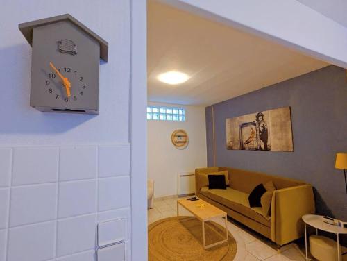 a living room with a couch and a clock on the wall at Maison atypique avec garage 2 roues - Proche Gare in Le Havre
