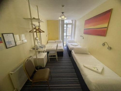 Pokój z 4 łóżkami, stołem i krzesłami w obiekcie Manor Hotel w Londynie