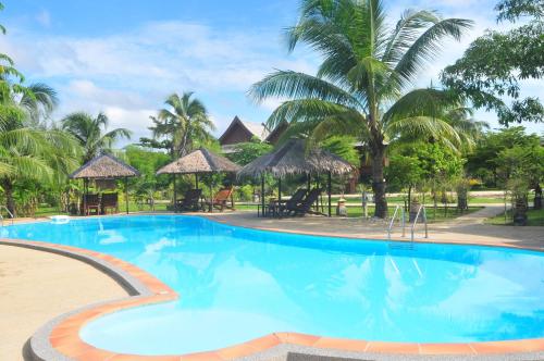 a swimming pool at a resort with palm trees at The Hip Resort @ Khao Lak in Bang Sak