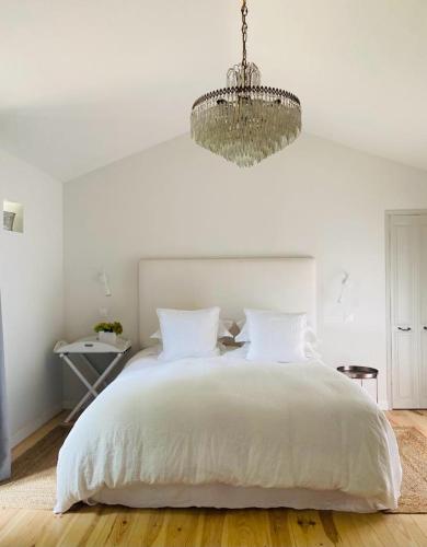 - une chambre avec un lit blanc et un lustre dans l'établissement The Old Stables, à Saint-Jean-dʼAngély