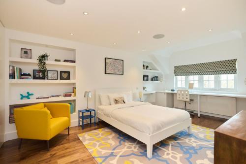 a bedroom with a bed and a yellow chair at The Clapham Crib - Spacious 4BDR House with Patio in London