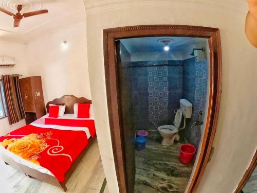 a bedroom with a red bed and a bathroom with a toilet at Backpackers Karma Home stay in Khajurāho