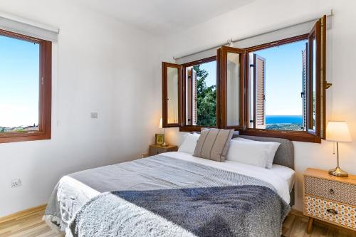 a bedroom with a bed and two windows at 1 bedroom Apartment Pyrgos with beautiful sea and sunset views, Aphrodite Hills Resort in Kouklia