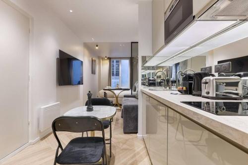 une cuisine avec un comptoir, des chaises et une table dans l'établissement Magnifique appartement Magenta, à Paris
