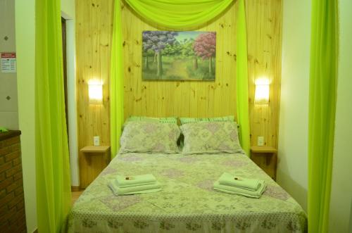a bedroom with a green bed with two towels on it at Pousada Cantinho Colibri in Monte Verde