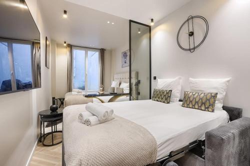 une chambre avec un grand lit blanc avec deux chaises dans l'établissement Magnifique appartement Magenta, à Paris