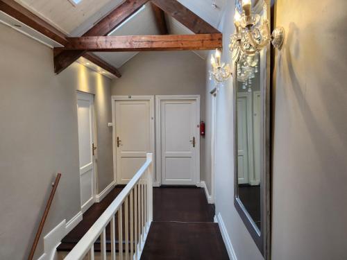 a hallway with white walls and a ceiling with a chandelier at Landhuis de heibloem in Heythuysen